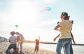 Happy families flying with kite and having fun on the beach - Parents playing with children outdoor - Love, and weekend holidays Royalty Free Stock Photo