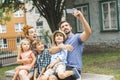 Happy familly of five in the park taking portrait with cellphone