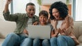 Happy family African American parents mum dad and Caucasian little boy kid child teenager son use laptop playing video Royalty Free Stock Photo