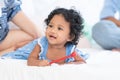 Happy family, African newborn 7 months old baby girl with black curly hair lying on bed and holding toy in hand, smiling and Royalty Free Stock Photo