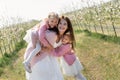 Happy family in the Apple orchard. Mom and two twin daughters have fun and hug Royalty Free Stock Photo