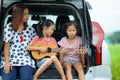 Happy family asian children and their mother playing guitar and singing a song together in a car trunk