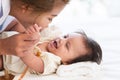 Happy family. Asian mother holding her adorable Caucasian newborn 3 months old baby girl hands, having fun playing together while Royalty Free Stock Photo