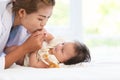 Happy family. Asian mother kissing her adorable Caucasian newborn 3 months old baby girl hands, having fun playing together while Royalty Free Stock Photo