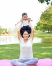 Happy family Asian mother lifting up son on her shoulder lying on green lawn at park Royalty Free Stock Photo