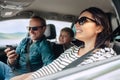 Happy family auto traveling concept image. Car interior view of female driving, man dealing mobile phone and little son smiling