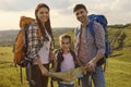 Happy family with backpacks hiking in nature.