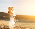 Happy family at beach. mother hugging baby daughter at sunset