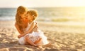 Happy family at beach. mother hugging baby daughter at sunset