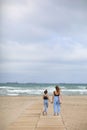 Happy family on beach vacation. Back view of mother and little daughter are walking together and holding hands on beach Royalty Free Stock Photo