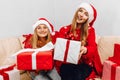 Happy family  beautiful mother and her little daughter in Santa Claus hats  are sitting at home on the couch with Christmas gifts Royalty Free Stock Photo