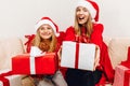 Happy family  beautiful mother and her little daughter in Santa Claus hats  are sitting at home on the couch with Christmas gifts Royalty Free Stock Photo