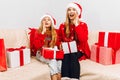 Happy family  beautiful mother and her little daughter in Santa Claus hats  are sitting at home on the couch with Christmas gifts Royalty Free Stock Photo