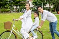 Happy family with bicycle outdoors on summer day, Asian father and mother with daughter enjoying riding a bike outdoors in a park Royalty Free Stock Photo