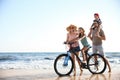 Happy family with bicycle on beach near sea