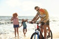 Happy family with bicycle on sandy beach near sea