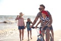 Happy family with bicycle on sandy beach near sea