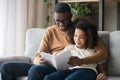 Happy family black father and kid daughter reading story book