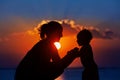 Black silhouette of mother, baby son walk by sea beach Royalty Free Stock Photo