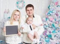 Happy family with a blank card while standing near the Christmas tree Royalty Free Stock Photo