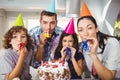 Happy family blowing party horn during birthday celebration