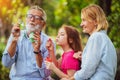 Happy family blowing soap bubbles in the park. Royalty Free Stock Photo