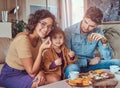 Family Breakfast. Young attractive family having breakfast at home sitting on a sofa. Royalty Free Stock Photo