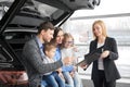 Happy family buying new comfortable black car in auto salon Royalty Free Stock Photo