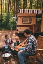 Happy family on a camping trip relaxing in the autumn forest. Camper trailer. Fall season outdoors trip Royalty Free Stock Photo