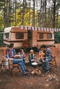 Happy family on a camping trip relaxing in the autumn forest. Camper trailer. Fall season outdoors trip Royalty Free Stock Photo