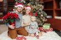 Happy family celebrating Christmas or New Year winter holiday at home. Smiling Caucasian mother and father with baby girl sitting Royalty Free Stock Photo