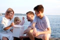 Happy family celebrating little girl's birthday on the seashore mom brings a box with cake girl opens a gift dad mom Royalty Free Stock Photo