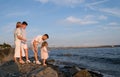 Happy family celebrating little girl& x27;s birthday on the seashore mom brings a box with cake girl opens a gift dad mom Royalty Free Stock Photo