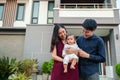 happy family, cheerful father and mother holding and playing with newborn baby while standing in front of their house Royalty Free Stock Photo