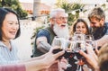 Happy family cheering and toasting with red wine glasses at dinner outdoor - People with different ages and ethnicity having fun Royalty Free Stock Photo