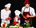 Happy family in chef uniform cooking at home. Family preparing healthy tasty food together in kitchen. Parents with Royalty Free Stock Photo