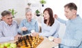 Happy family chess game time at nursing home for elderly. Parents with children have fun talk and leisure. Senior couple
