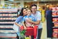 Family with child and shopping cart buying food at grocery store or supermarket Royalty Free Stock Photo