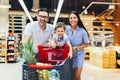 Family with child and shopping cart buying food at grocery store or supermarket Royalty Free Stock Photo