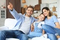 Happy family with child sitting on sofa watching tv, young parents embracing daughter relaxing on couch together Royalty Free Stock Photo