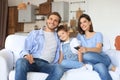 Happy family with child sitting on sofa watching tv, young parents embracing daughter relaxing on couch together Royalty Free Stock Photo