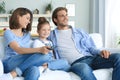 Happy family with child sitting on sofa watching tv, young parents embracing daughter relaxing on couch together Royalty Free Stock Photo