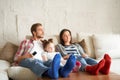 Happy family with child sitting on sofa watching tv, young parents embracing daughter relaxing on couch together Royalty Free Stock Photo