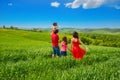 Happy family with children having fun outdoors on green field, spring family vacation with kids in Tuscany, Italy