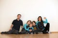 Happy family with children, holding keys from a new home, sitting on the floor