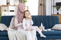 Happy family. Children hygiene. Young muslim mother in headscarf, holds her cute little daughter on the knees, while Royalty Free Stock Photo