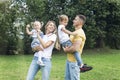 Happy family with children in the park on a sunny day. Mom, dad and little daughter and son in jeans and white t-shirts laugh and Royalty Free Stock Photo