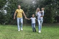 Happy family with children in the park on a sunny day. Mom, dad and little daughter and son in jeans and white t-shirts laugh and Royalty Free Stock Photo