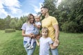 Happy family with children in the park on a sunny day. Mom, dad and little daughter and son in jeans and white t-shirts laugh and Royalty Free Stock Photo