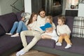 Happy family with children reading book together sitting on sofa Royalty Free Stock Photo